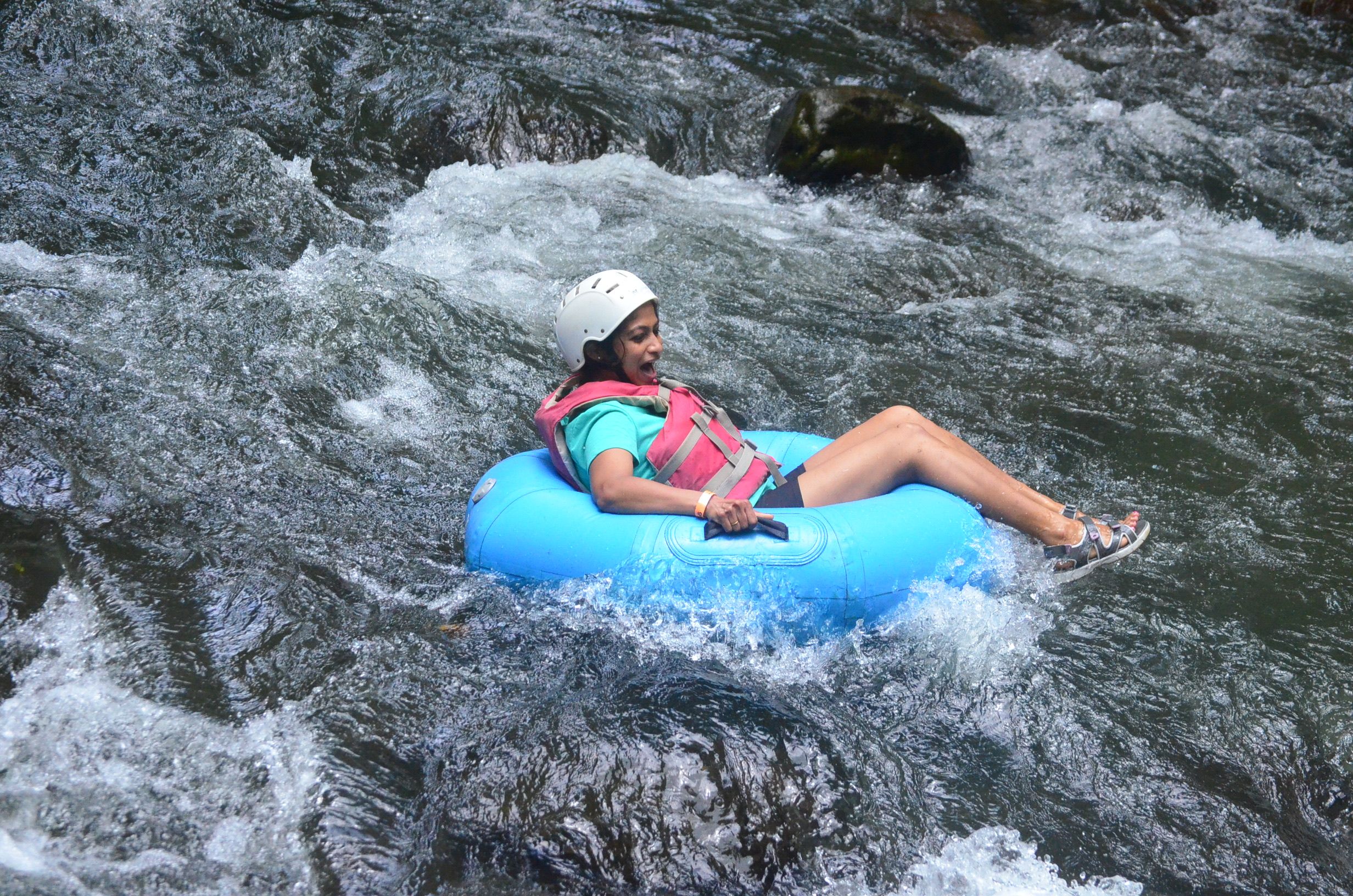 A woman joyfully riding an inflatable tube down a rushing river, enjoying a thrilling outdoor adventure.